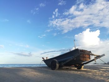 Abandoned ship moored on beach against sky