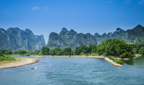 Scenic view of river and mountains against clear blue sky