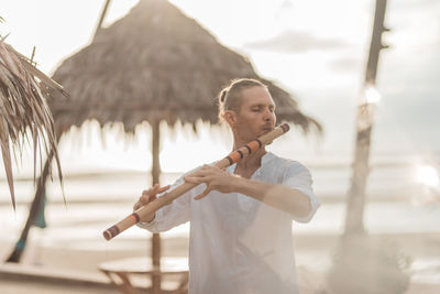 Man playing wind instrument on the beach at sunrise