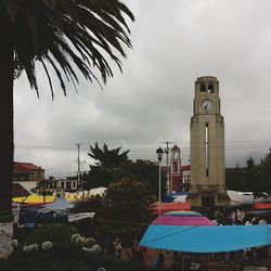 Palm trees and buildings against cloudy sky