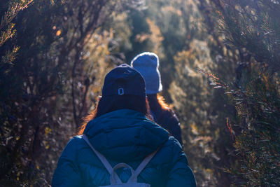 Rear view of person in snow covered forest