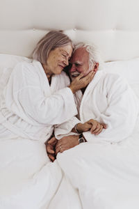 Smiling romantic senior couple on bed in hotel room