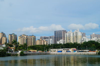 Buildings by river against sky in city