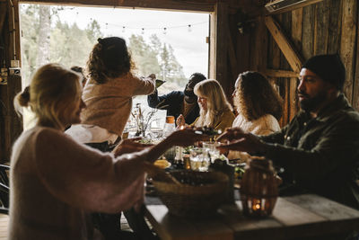 Female passing food bowl to male friend over dining table during social event