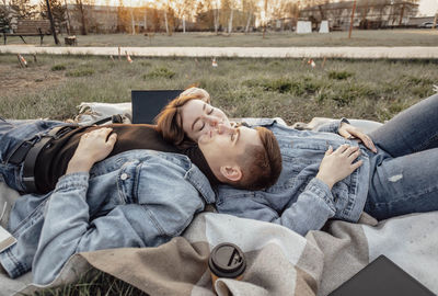 Young couple finds perfect balance between work and life, relaxing on picnic blanket in park, laptop