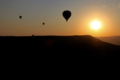Silhouette of hot air balloons flying over landscape