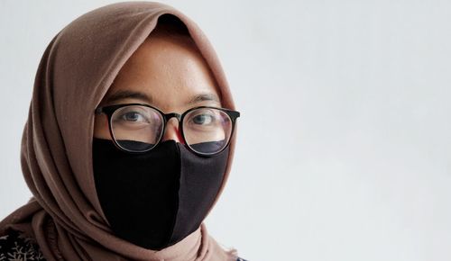 Portrait of young man wearing eyeglasses against white background