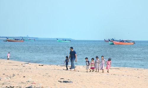 People on beach against clear sky