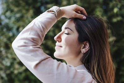 Close-up portrait of young woman with arms raised