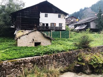 Old house amidst trees and buildings against sky