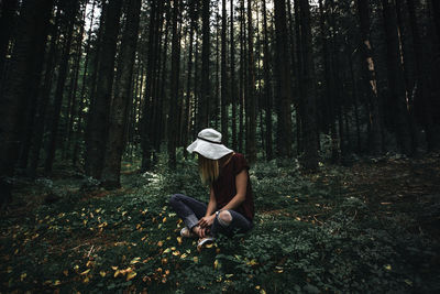 Woman sitting against trees in forest