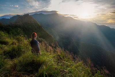 Rear view of woman looking at mountains against sky