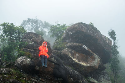 Rear view of man standing on rock against mountain