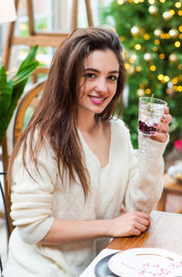 Portrait of smiling young woman with drink at table