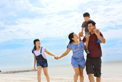 Happy family enjoying together on land against sky
