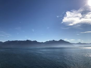 Scenic view of sea and mountains against blue sky