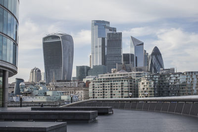 Modern buildings by river against sky in city