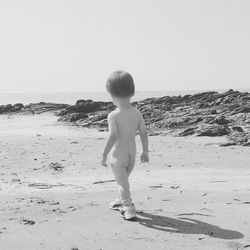 Full length of shirtless boy on beach against clear sky