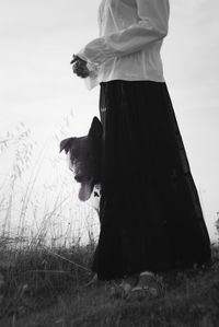 Low section of woman with dog standing on field