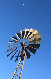 Windmill and lunar ghost against a clear blue sky