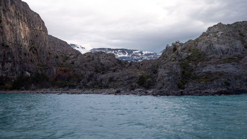 Scenic view of sea and mountains against cloudy sky