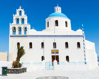 Low angle view of church in oia village against clear blue sky at santorini