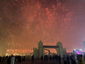 Group of people on fireworks against sky at night