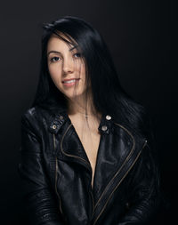 Portrait of smiling young woman against black background