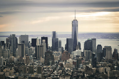 Aerial view of buildings in city against cloudy sky