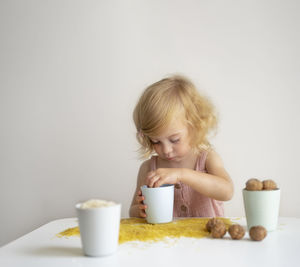 Baby girl, toddler playing with grain, nuts, pasta and rice at table.sensoric early development