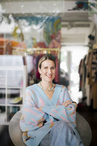 Portrait of female entrepreneur sitting in clothing store