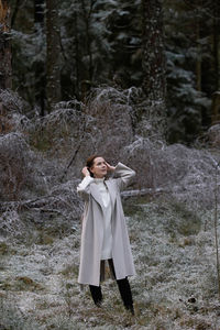 Full length of woman standing on field in forest