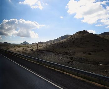 Road leading towards mountains against sky