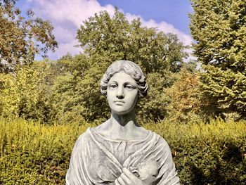 Low angle view of statue of young woman standing on grassy field