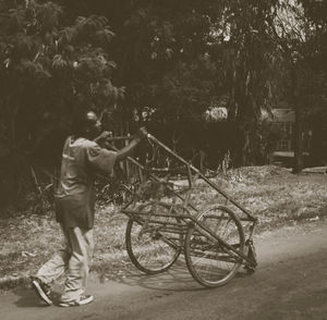 Man with bicycle standing on tree