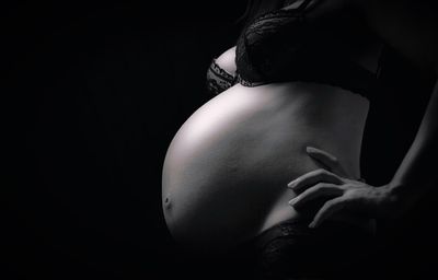 Side view of woman touching hair against black background