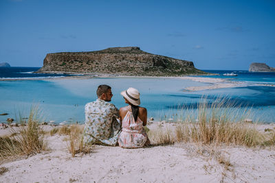 Rear view of friends on beach against sky