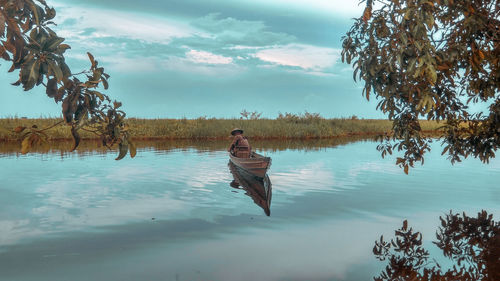 Man on boat in lake against sky