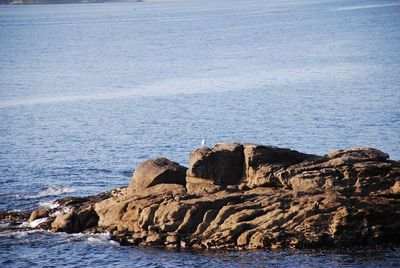 Rock formation on sea shore against sky