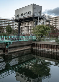 Bridge over lake by buildings against sky