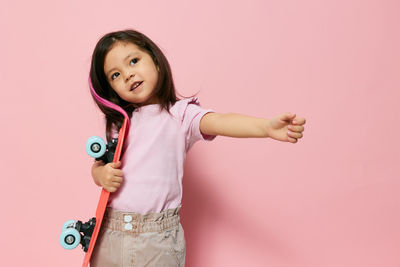 Portrait of smiling young woman holding toy against pink background