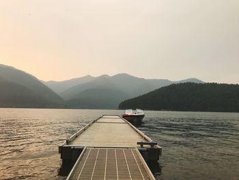 Pier over lake against sky during sunset