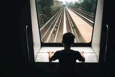 Rear view of a boy looking through window