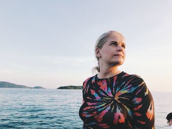 Woman standing by sea against sky
