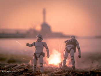 Friends standing on land against sky during sunset