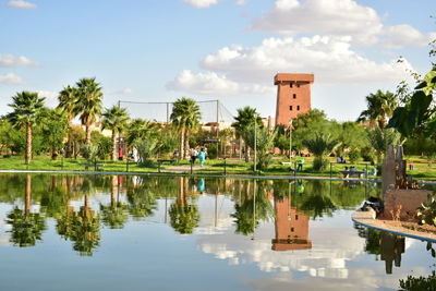 Reflection of trees and building in lake against sky