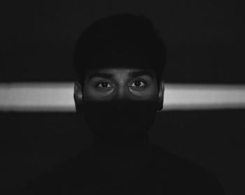 Portrait of young woman against black background