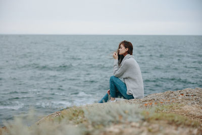 Young woman sitting against sea