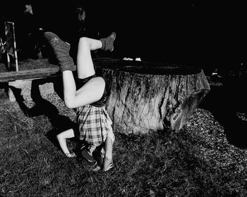 Mid adult woman doing headstand on grassy field at night