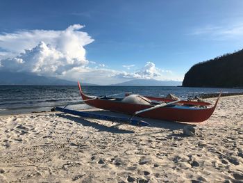 Fishing boat on beach against sky